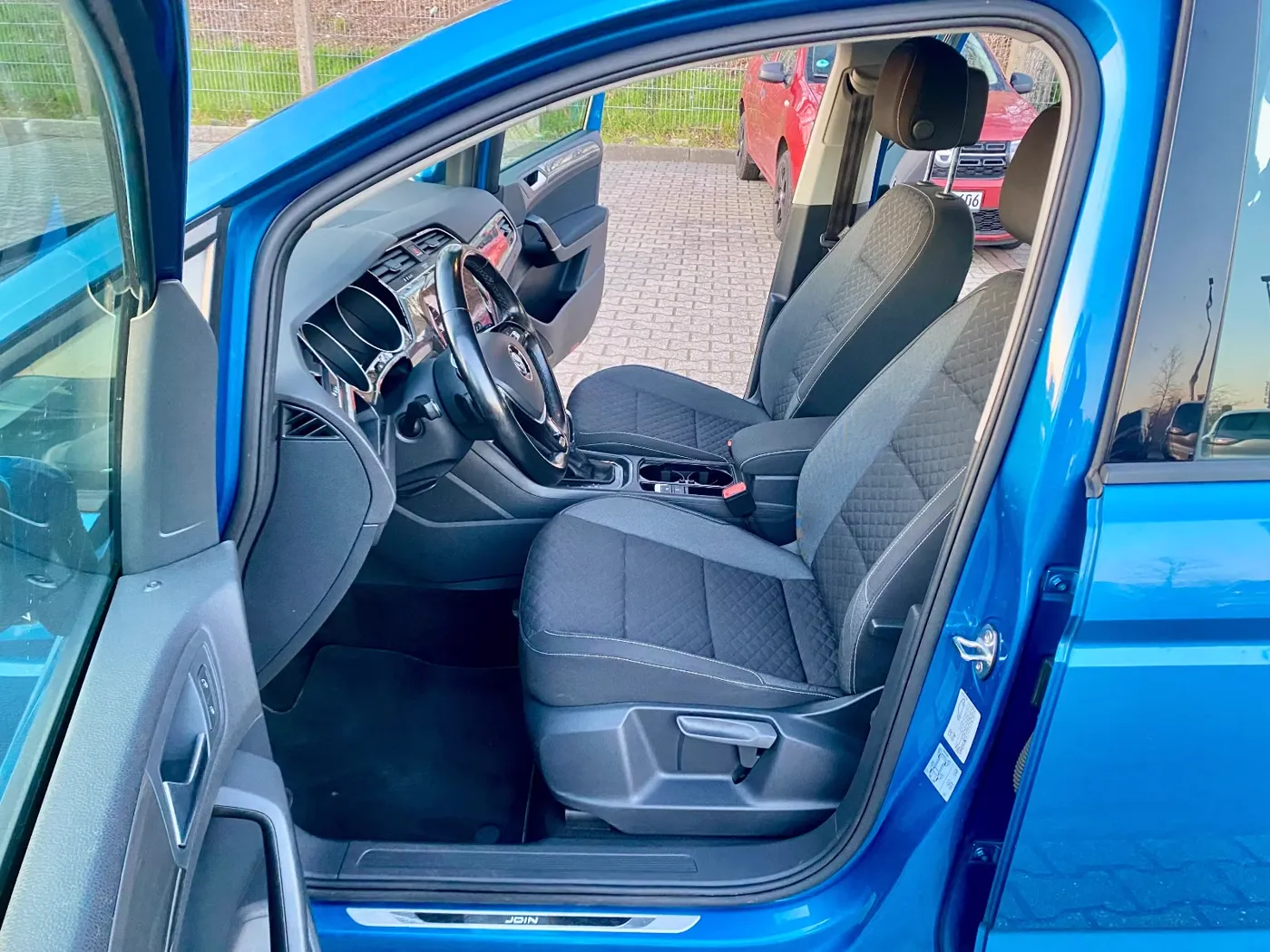 Geöffnete Fahrertür eines blauen VW Touran, Blick auf Fahrersitz und Lenkrad, auf dem Hof von S.A.S Automobile